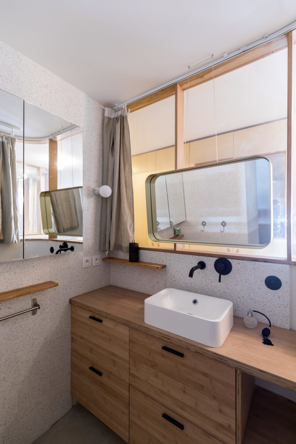 Salle de bains - Miroir suspendu, mur en terrazzo blanc. Meuble /commode en bambou avec vasque