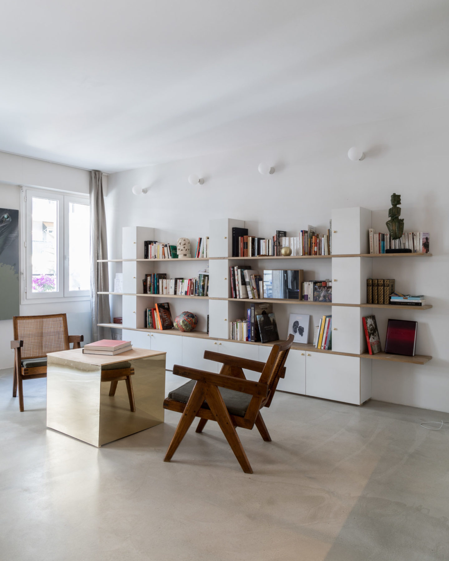 Séjour - Fauteuils Pierre Jeanneret, Le Corbusier. Sol ciment vernis, table cube miroir bronze