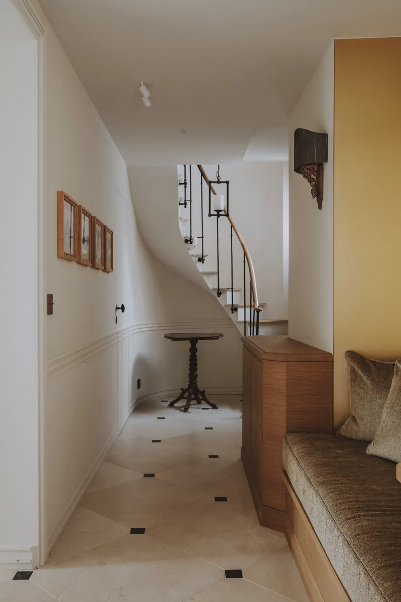 Vestibule parisien avec sol en pierre, cabochons foncés et banquette d’entrée en merisier.