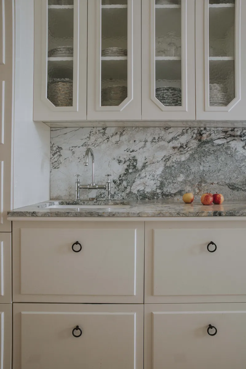 Détail d’une cuisine parisienne classique blanche avec agencement sur mesure.