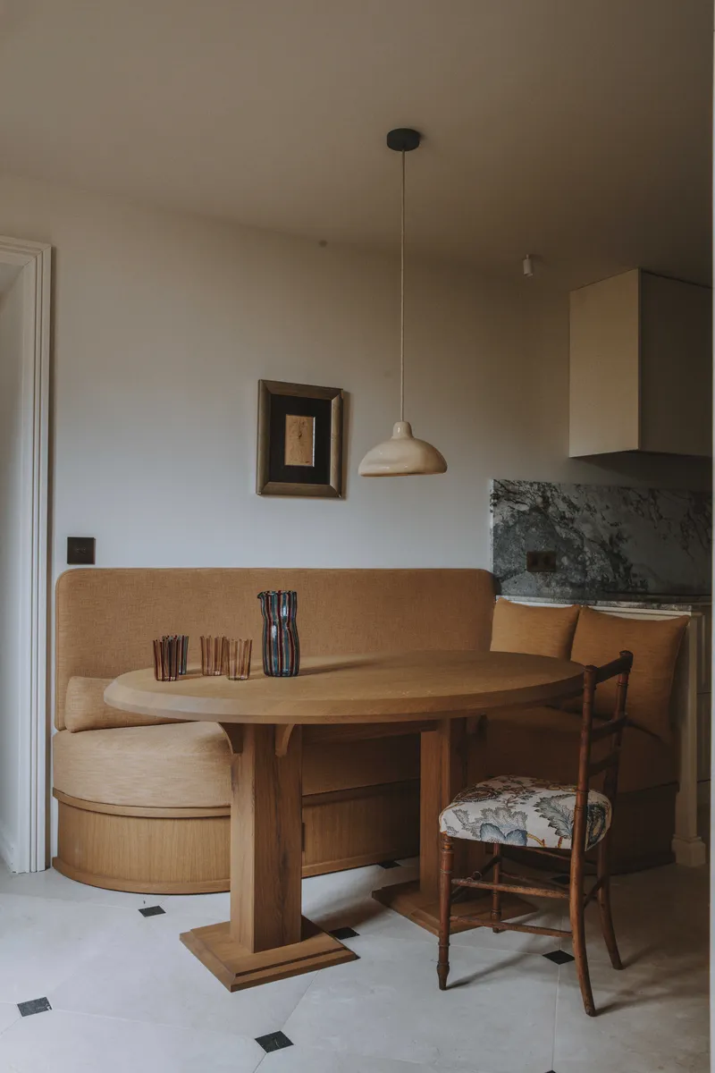 Banquette de cuisine en velours et table style Perriand dans un ensemble lumineux.