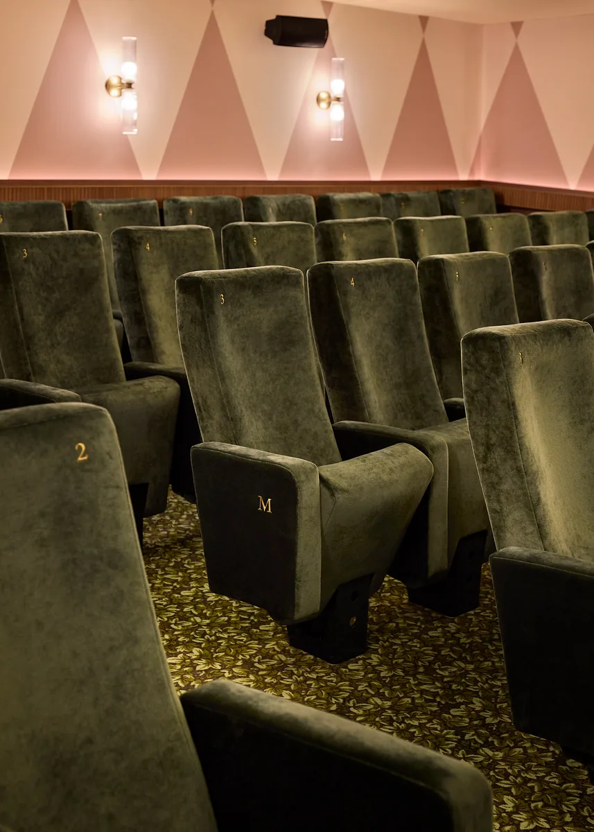 Green velvet cinema seats in L'Audito, with gilded numbering and bespoke foliage carpet.