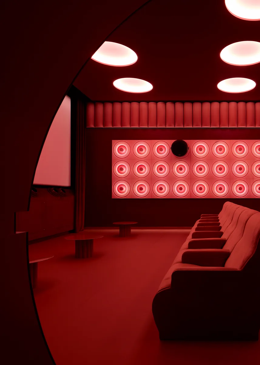 Screen and velvet curtain in Le Club modular room, with oval ceiling lights and deep red floor and walls.
