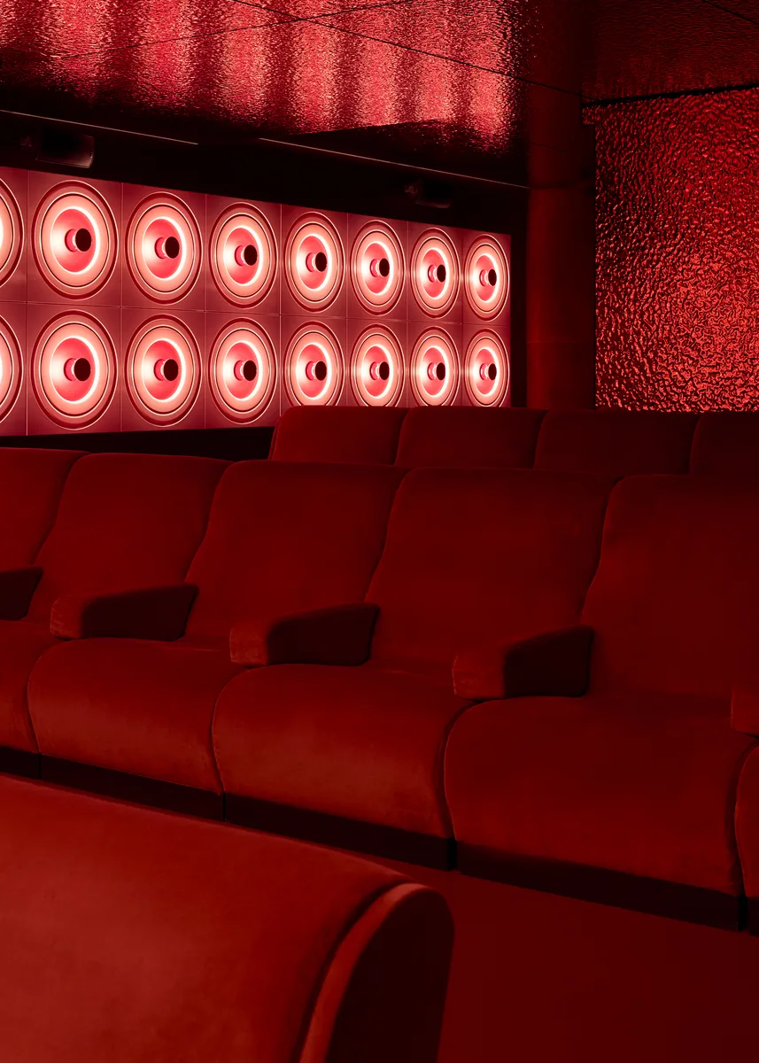 Modular velvet cinema benches, with a hammered red glass ceiling and a light wall.