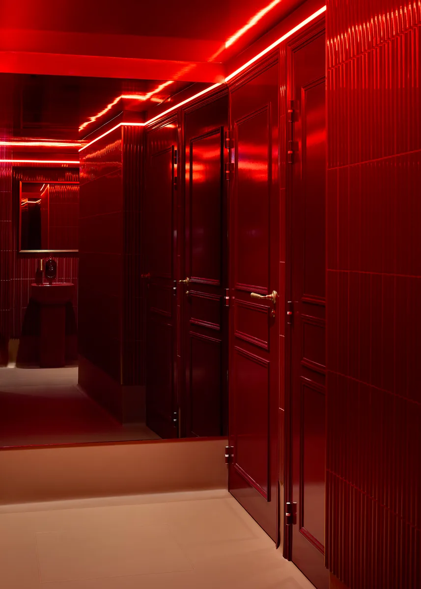 Red lacquered cinema restrooms, with fluted tile, panelled doors and mirrors.