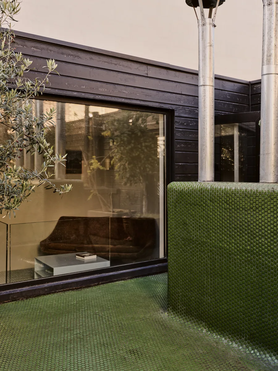 Extension en bois brûlé sur le toit-terrasse, mosaïque vert pop et grande baie vitrée.