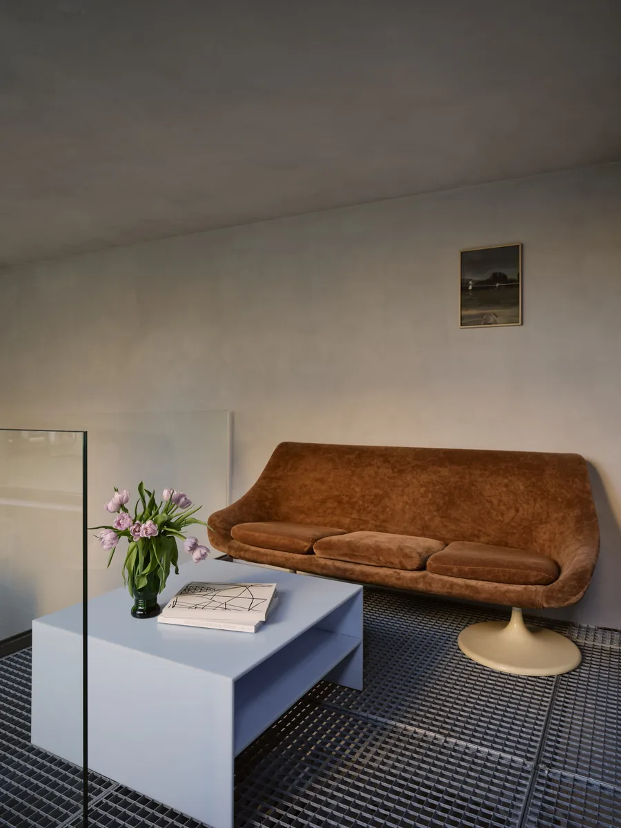 Mezzanine au sol en métal perforé avec canapé Tulipe d'Eero Saarinen en daim et table basse en résine.