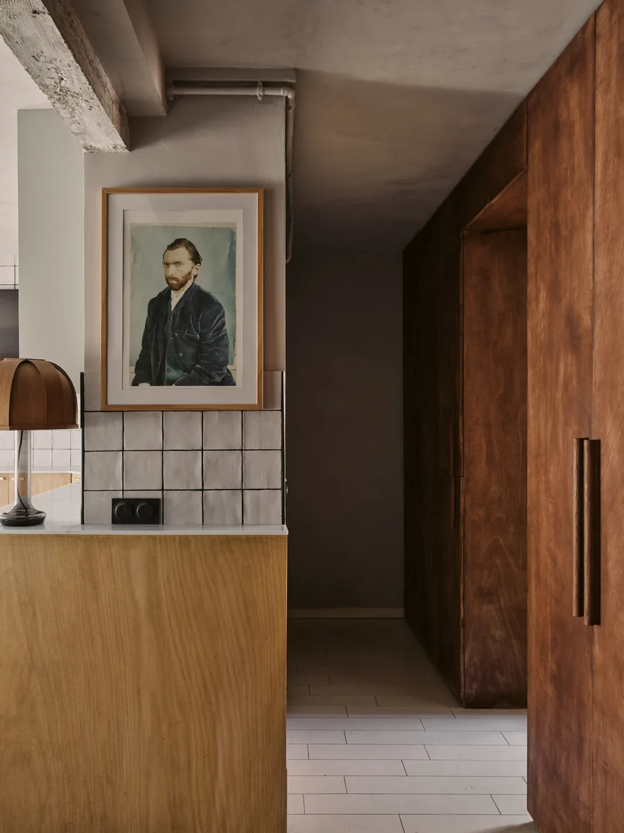 Cuisine en bois clair avec portrait de Van Gogh, carrelage émaillé, applique en laiton et dressing en acajou.